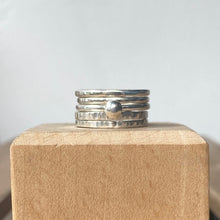 Load image into Gallery viewer, Stack of silver rings on a wooden block with a plain background