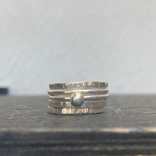 Load image into Gallery viewer, Stack of silver rings on a dark surface with a light gray background